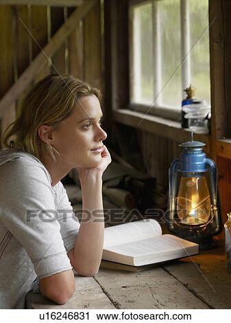 Woman sitting at a table in cabin with book. View Large Photo Image Stock Image - Woman sitting at a table in cabin with book.. Fotosearch
