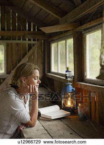 Woman with eyes closed sitting at a table in cabin with book. View Large Photo Image Stock Photo - Woman with eyes closed sitting at a table in cabin with book.. Fotosearch