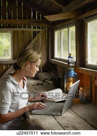 Woman with laptop and book sitting at table in cabin. View Large Photo Image Stock Image - Woman with laptop and book sitting at table in cabin.. Fotosearch