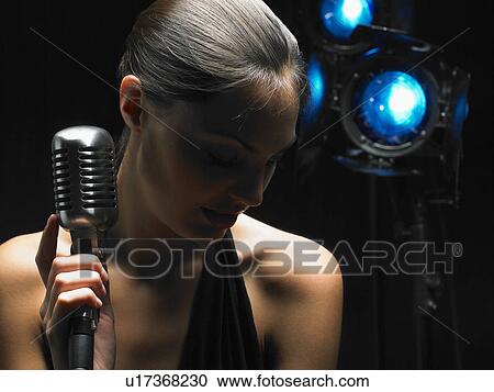 Stock Image - Close up of woman holding microphone.. Fotosearch