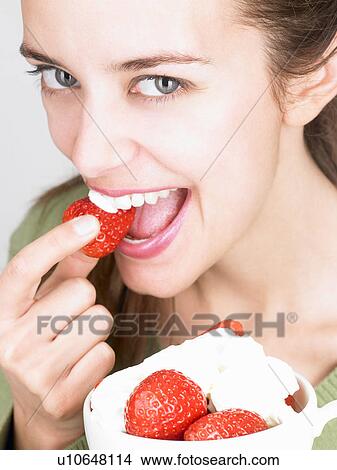 Picture - Woman eating strawberries. Fotosearch