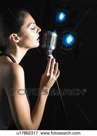 Stock Photo - Woman singing into microphone.. Fotosearch