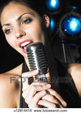 Woman singing into microphone. View Large Photo Image Stock Photograph - Woman singing into microphone.. Fotosearch