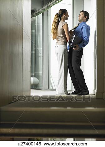 Stock Photograph - A woman talking to a man in a hallway. Fotosearch