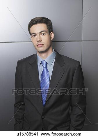 Businessman standing in front of a white wall View Large Photo Image Stock Image - Businessman standing in front of a white wall. Fotosearch