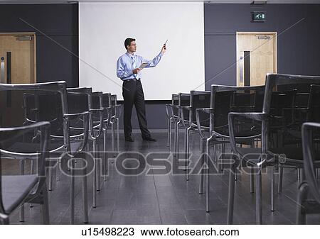 Stock Image - Man practicing speech in empty presentation room. Fotosearch