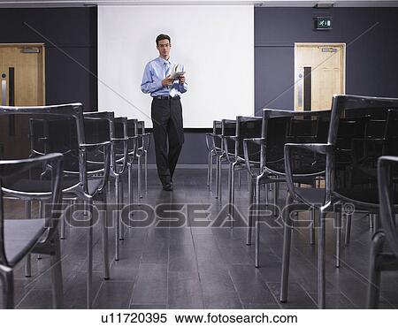 Stock Photography - Man practicing speech in empty presentation room. Fotosearch