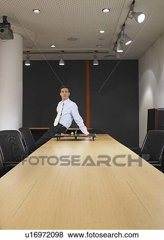 Portrait of young man sitting at boardroom table with miniature table tennis set View Large Photo Image Stock Photo - Portrait of young man sitting at boardroom table with miniature table tennis set. Fotosearch