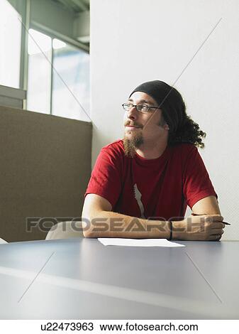 Young man sitting at desk portrait View Large Photo Image Stock Image - Young man sitting at desk portrait. Fotosearch
