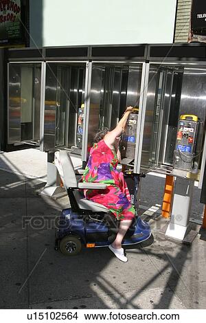 A woman trying to use non accessible pay phones. View Large Photo Image Picture - A woman trying to use non accessible pay phones.. Fotosearch