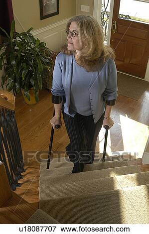 Stock Photo - A woman using a wheelchair enters her house.. Fotosearch
