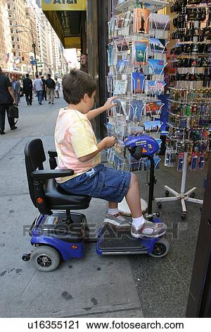 Boy using a scooter/cart purchasing a post card on the streets of New York City. View Large Photo Image Stock Image - Boy using a scooter/cart purchasing a post card on the streets of New York City.. Fotosearch