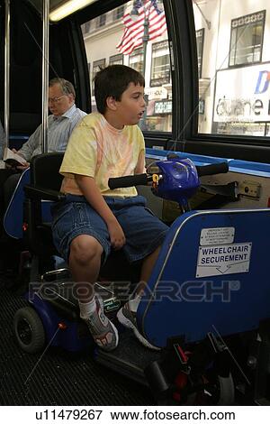 Stock Photo - Boy with Muscular Dystrophy, utilizing a scooter/cart for mobility, using a city bus.. Fotosearch