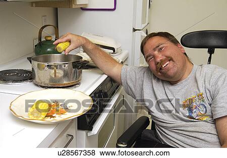 Man with a disability cooking his dinner in his kitchen, in his own apartment. View Large Photo Image Stock Photo - Man with a disability cooking his dinner in his kitchen, in his own apartment.. Fotosearch
