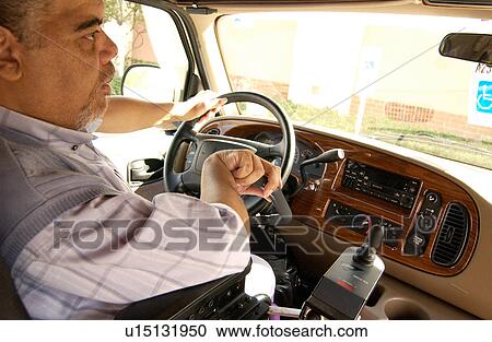 Stock Image - Man with a disability driving his van equipped with hand controls.. Fotosearch