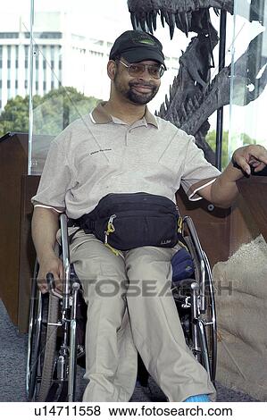 Man with a disability, utilizing a wheelchair for mobility, visiting an exhibit. View Large Photo Image Stock Photo - Man with a disability, utilizing a wheelchair for mobility, visiting an exhibit.. Fotosearch