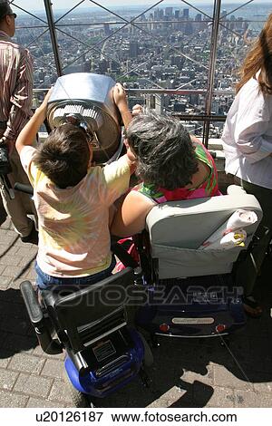 Mother and son, both with disabilities and utilizing scooters for mobility, enjoying a panoramic view of New York City. View Large Photo Image Stock Photo - Mother and son, both with disabilities and utilizing scooters for mobility, enjoying a panoramic view of New York City.. Fotosearch