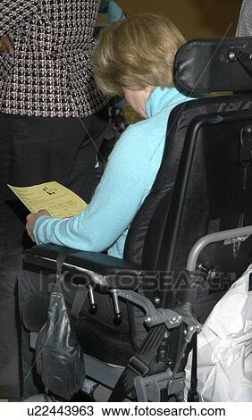 Woman with disabilities sitting in her electric wheelchair, reading a paper in a group of other people. View Large Photo Image Stock Image - Woman with disabilities sitting in her electric wheelchair, reading a paper in a group of other people.. Fotosearch
