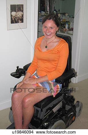 Young woman (electric wheelchair user) smiles at the camera in her accessible home. View Large Photo Image Picture - Young woman (electric wheelchair user) smiles at the camera in her accessible home.. Fotosearch