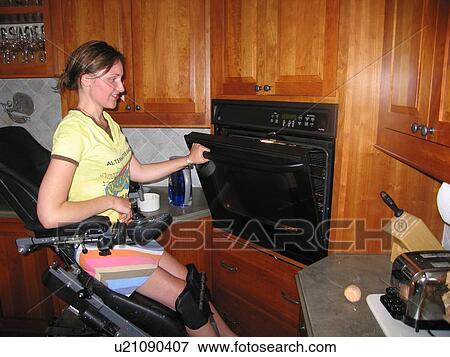 Young woman (electric wheelchair user) checks baked goods in her accessible oven. View Large Photo Image Stock Photo - Young woman (electric wheelchair user) checks baked goods in her accessible oven.. Fotosearch
