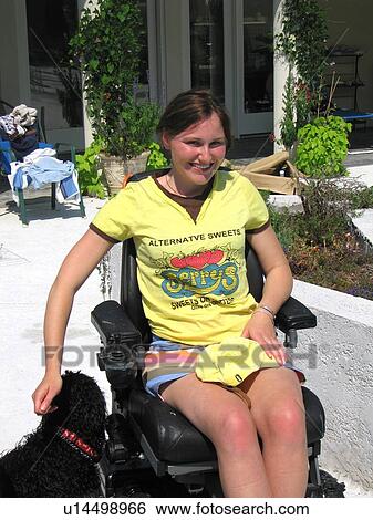Young woman (electric wheelchair user) pets her dog in front of her accessible home View Large Photo Image Stock Photograph - Young woman (electric wheelchair user) pets her dog in front of her accessible home. Fotosearch