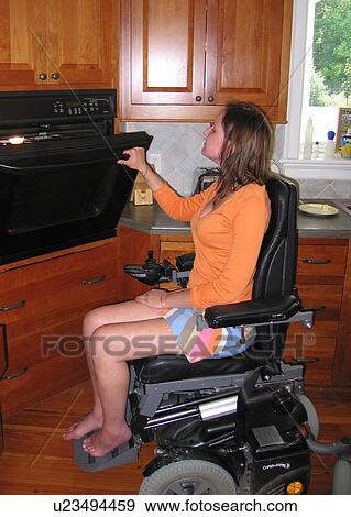 Young woman (wheelchair user) checks items baking in the oven in her accessible kitchen. View Large Photo Image Stock Photo - Young woman (wheelchair user) checks items baking in the oven in her accessible kitchen.. Fotosearch
