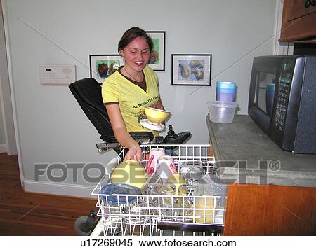 Young woman (wheelchair user) empties clean dishes from an accessible dishwasher. View Large Photo Image Stock Photography - Young woman (wheelchair user) empties clean dishes from an accessible dishwasher.. Fotosearch