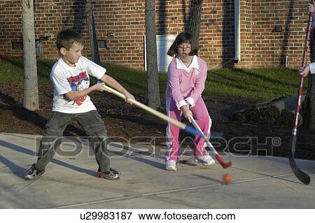 A girl with Down syndrome guarding the hockey puck during an active pass in a game of street hockey with other children. View Large Photo Image Stock Photo - A girl with Down syndrome guarding the hockey puck during an active pass in a game of street hockey with other children.. Fotosearch