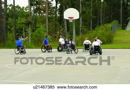 Stock Photography - A group of men playing a game of wheelchair basketball at their local recreation center.. Fotosearch