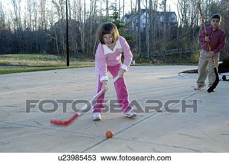 Stock Image - Girl with Down syndrome passing a hockey puck to a little boy during a game of street hockey.. Fotosearch