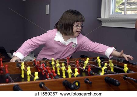 Girl with Down syndrome playing at a foosball table. View Large Photo Image Stock Photo - Girl with Down syndrome playing at a foosball table.. Fotosearch