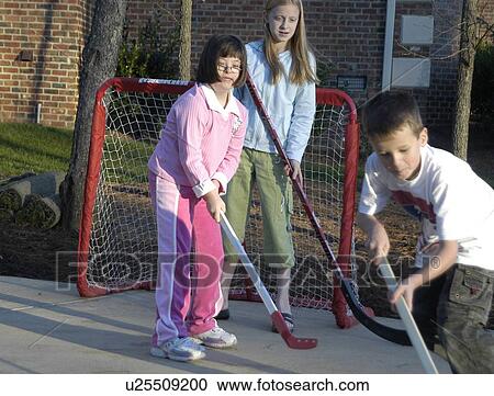 Stock Image - Girl with Down syndrome playing street hockey with a group of children. Fotosearch