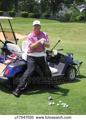 Stock Photography - Man standing beside a golf cart.. Fotosearch