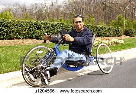 Stock Image - Man with a disability having fun riding his hand-controlled bicycle.. Fotosearch