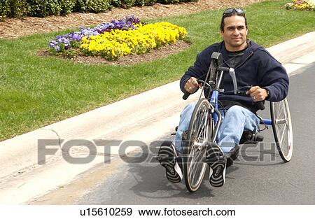 Stock Photo - Man with a disability having fun riding his hand-controlled bicycle.. Fotosearch