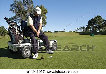 Man with a disability playing golf at a golf course while sitting on his scooter that he uses for mobility. View Large Photo Image Stock Photo - Man with a disability playing golf at a golf course while sitting on his scooter that he uses for mobility.. Fotosearch