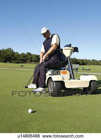 Man with a disability playing golf at a golf course while sitting on his scooter that he uses for mobility. View Large Photo Image Stock Photo - Man with a disability playing golf at a golf course while sitting on his scooter that he uses for mobility.. Fotosearch