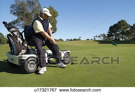 Man with a disability playing golf at a golf course while sitting on his scooter that he uses for mobility. View Large Photo Image Stock Photo - Man with a disability playing golf at a golf course while sitting on his scooter that he uses for mobility.. Fotosearch