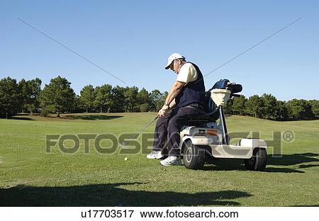 Stock Photo - Man with a disability playing golf at a golf course while sitting on his scooter that he uses for mobility.. Fotosearch