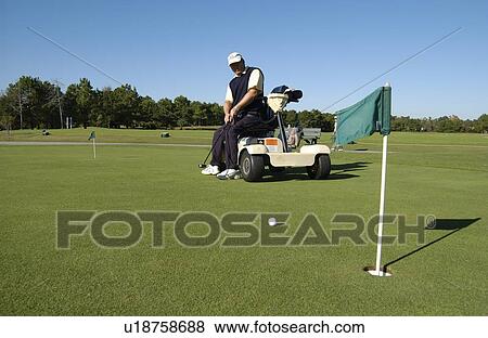 Stock Photo - Man with a disability playing golf at a golf course while sitting on his scooter that he uses for mobility.. Fotosearch