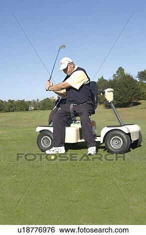 Stock Photograph - Man with a disability playing golf at a golf course while sitting on his scooter that he uses for mobility.. Fotosearch