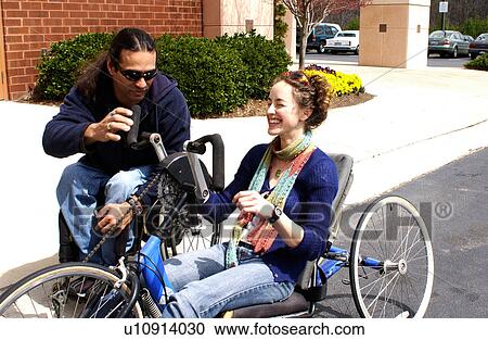 Man with a disability utilizing a wheelchair for mobility showing a friend how to ride a hand-controlled bicycle. View Large Photo Image Stock Image - Man with a disability utilizing a wheelchair for mobility showing a friend how to ride a hand-controlled bicycle.. Fotosearch