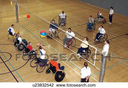 Stock Image - Several people with disabilities playing a game of wheelchair volleyball on an indoor court.. Fotosearch