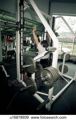 Woman with a disability, utilizing a wheelchair for mobility, working out in the weight room at her local fitness center. View Large Photo Image Stock Photo - Woman with a disability, utilizing a wheelchair for mobility, working out in the weight room at her local fitness center.. Fotosearch