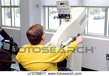 Young man with a disability, utilizing a wheelchair for mobility, working out at a local fitness center. View Large Photo Image Stock Photo - Young man with a disability, utilizing a wheelchair for mobility, working out at a local fitness center.. Fotosearch
