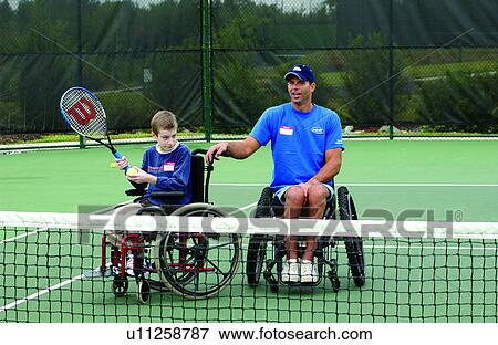 Young man with disabilities, with an instructor, both who utilize wheelchairs for mobility, learning to play tennis from his instructor at their local recreation center. View Large Photo Image Stock Photo - Young man with disabilities, with an instructor, both who utilize wheelchairs for mobility, learning to play tennis from his instructor at their local recreation center.. Fotosearch