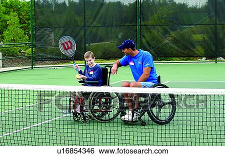 Young man with disabilities, with an instructor, both who utilize wheelchairs for mobility, learning to play tennis from his instructor at their local recreation center. View Large Photo Image Stock Photograph - Young man with disabilities, with an instructor, both who utilize wheelchairs for mobility, learning to play tennis from his instructor at their local recreation center.. Fotosearch