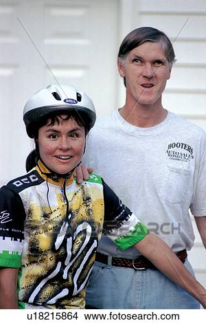 Young woman with a disability, accompanied by a friend, preparing to embark on a bicycle ride. View Large Photo Image Picture - Young woman with a disability, accompanied by a friend, preparing to embark on a bicycle ride.. Fotosearch
