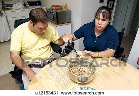 Stock Image - A couple, both with developmental disabilities, making a pie together in his kitchen.. Fotosearch