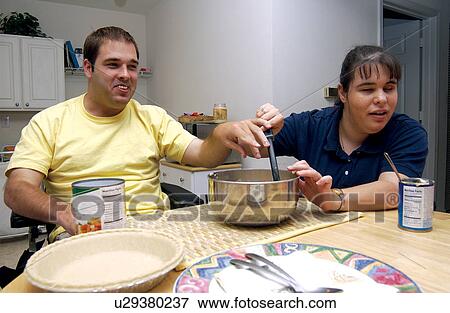 Stock Photo - A couple, both with developmental disabilities, making a pie together in his kitchen.. Fotosearch